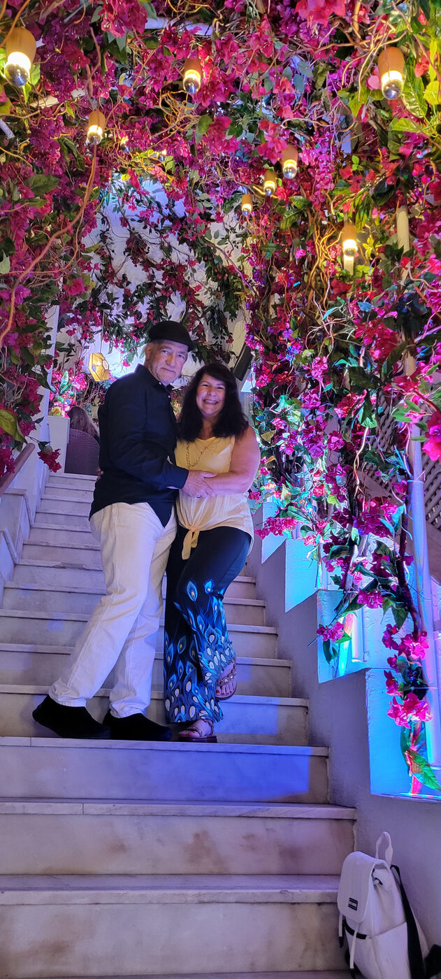 Hector and Bea Hernandez on flower-draped stairs in Santorini